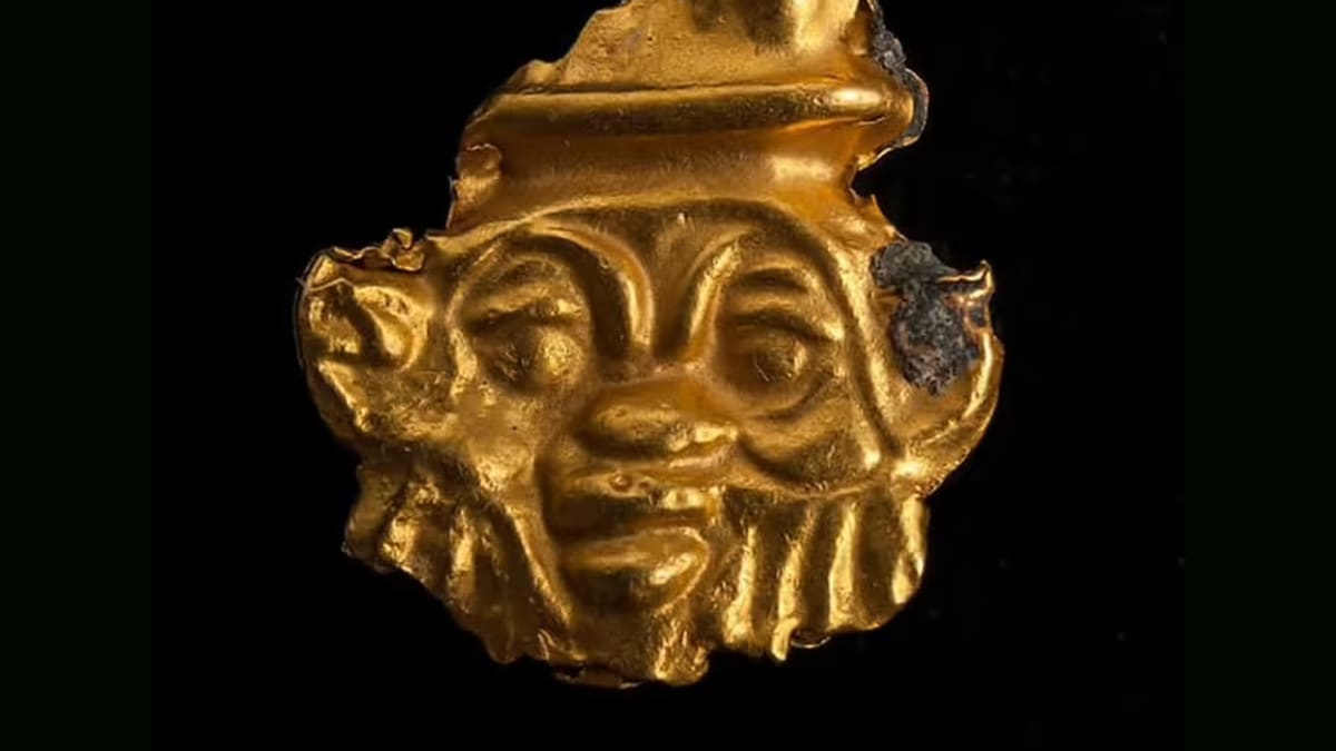 Kultainen amuletti, jossa on partaiset miehenkasvot. 