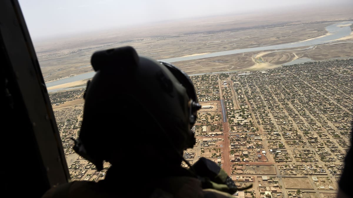 Malilainen kaupunki kuvattuna helikopterista, kuvan etualalla helikopterissa sotilas.