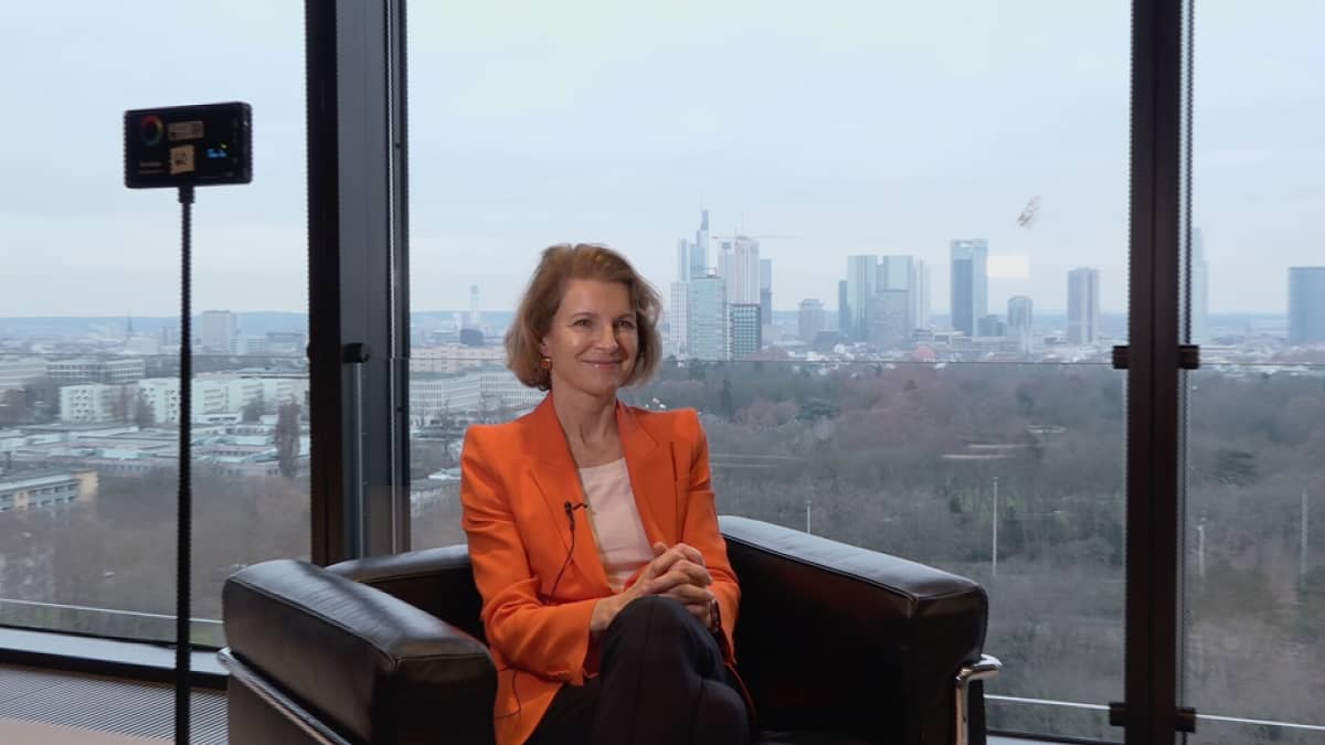 Sabine Mauderer istuu lasiseinän edessä Bundesbankin päärakennuksen yläkerroksessa, taustalla Frankfurt.