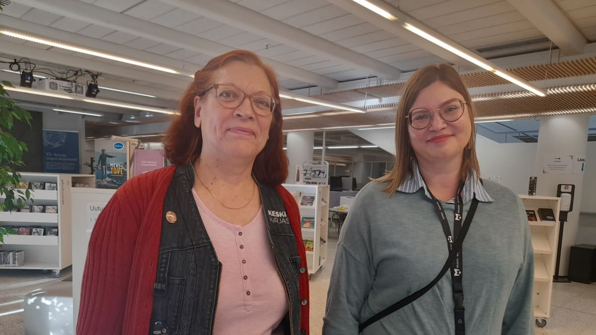 Kaksi naista seisoo hyllyjen edessä Jyväskylän kaupunginkirjastossa.