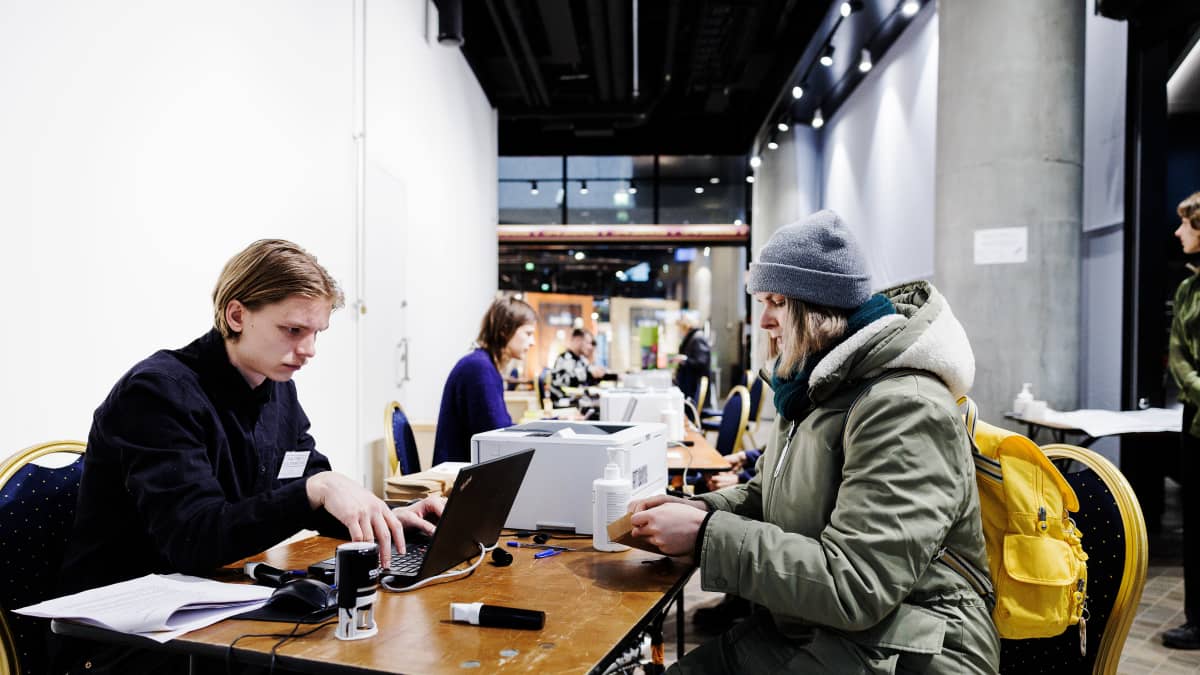 Vaalivirkailija ja naisäänestäjä ennakkoäänestyspaikalla.