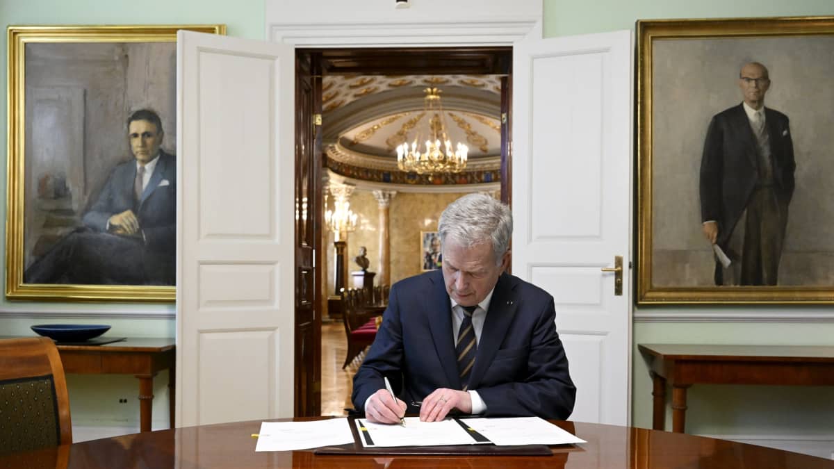 Presidentti Sauli Niinistö kirjoittaa kirjoituspöydän äärellä.