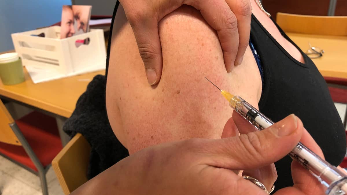 Kuvassa nainen saa rokotteen olkavarteen