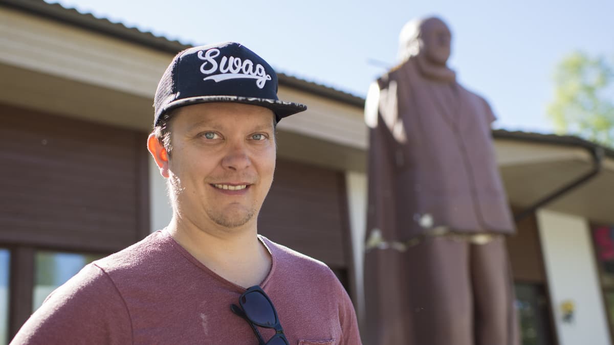 Mika Vacker poseeraa Juhani Tammisen patsaan edustalla.