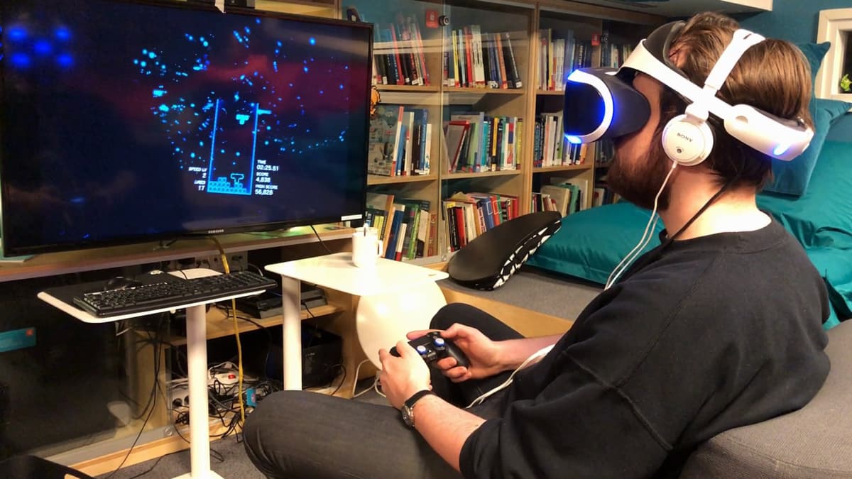Kuvassa mies pelaa VR-lasit päässä peliä