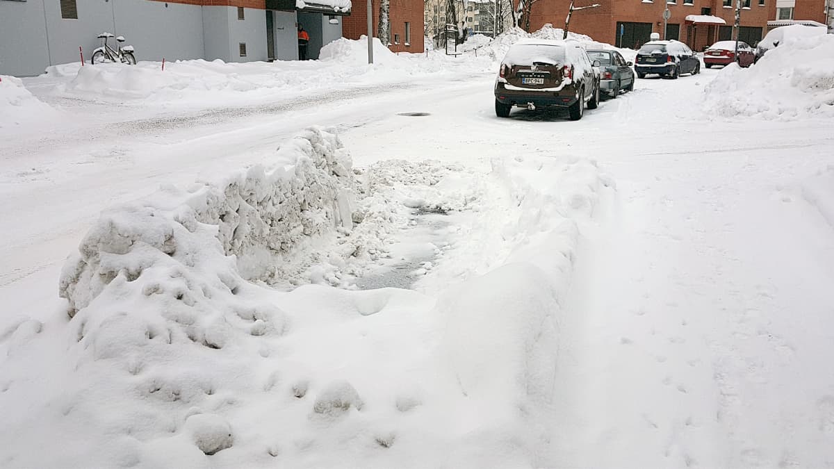 Parkkipaikan ympärille kertynyt lumivalli.