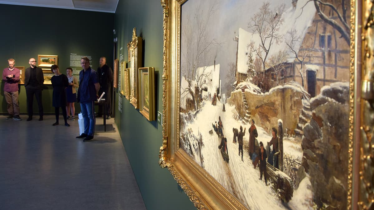 Ihmiset kauempana tarkastelevat etualalla näkyviä taideteoksia taidemuseossa