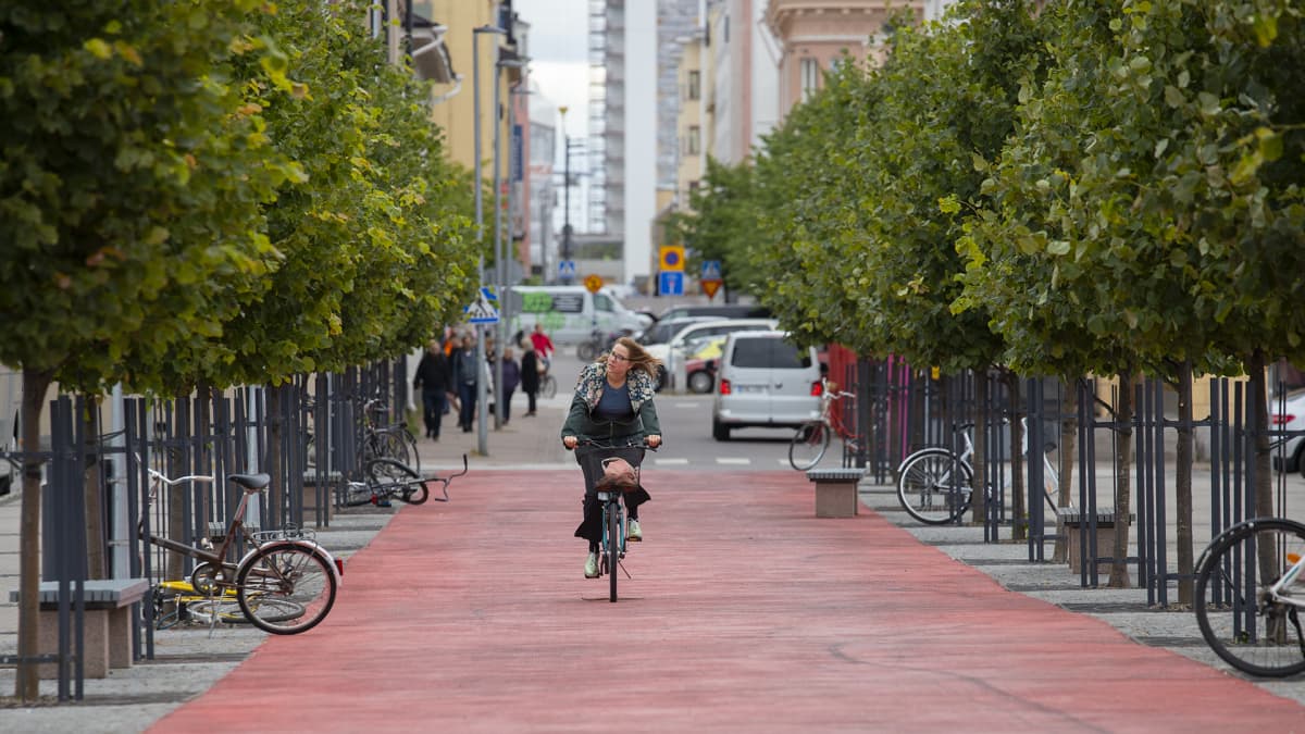 Nainen pyöräilee Oulun keskustassa pyöräbaanaa pitkin. 