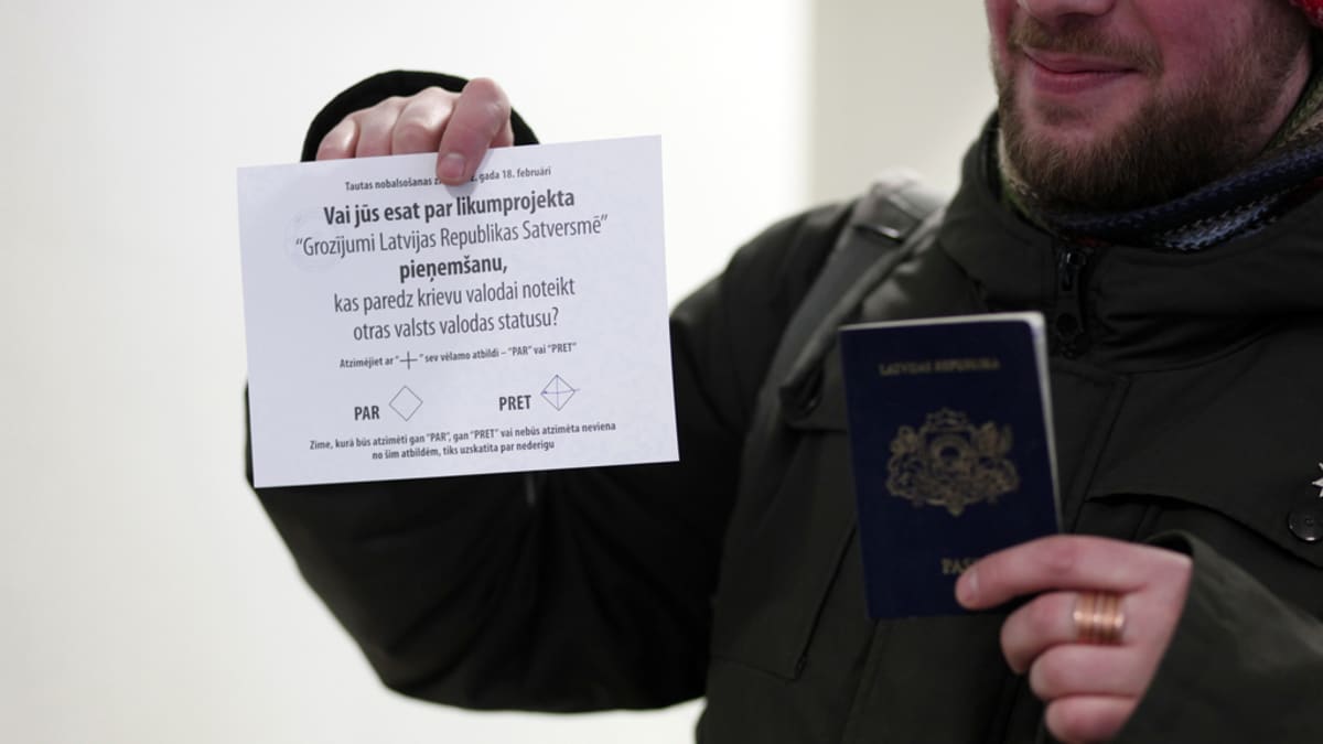 Latvian kansalainen pitää käsissään passia ja äänestyslappua.
