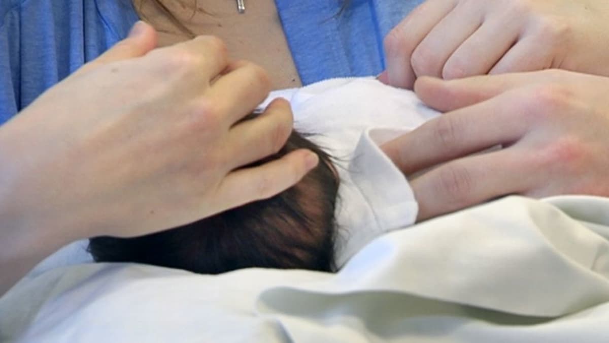 Vanhemmat silittävät vauvaa sairaalan synnytysosastolla.