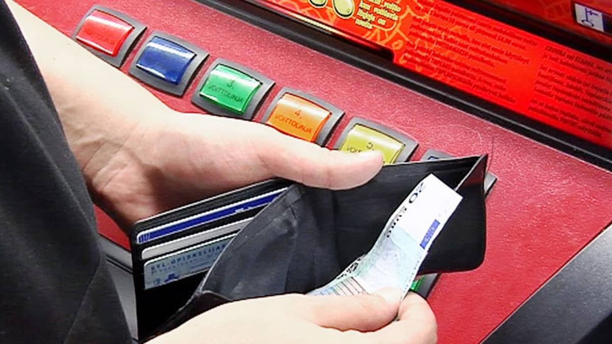 Nuori laskee rahojaan peliautomaatin äärellä.