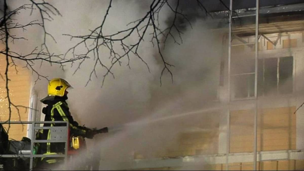 Palomies ruiskuttaa vettä rakennukseen ikkunoista.