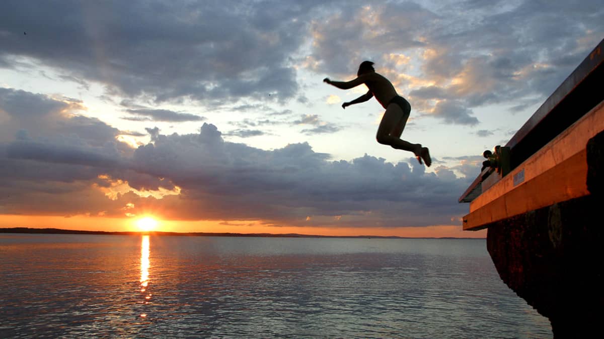 Boy jumping off a dock at sunset