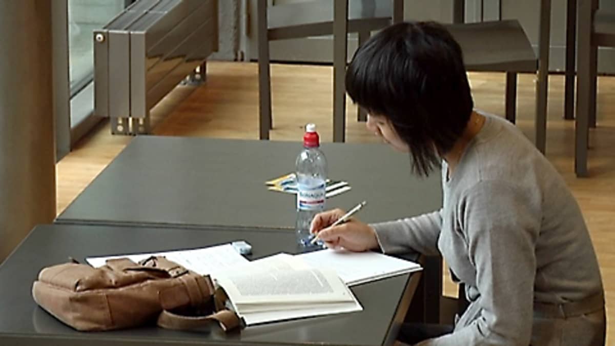 Opiskelija lukee pöydän ääressä tehden muistiinpanoja