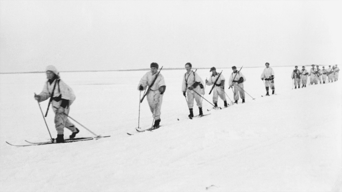 Lumipukuisia sotilaista hiihtää jäällä.