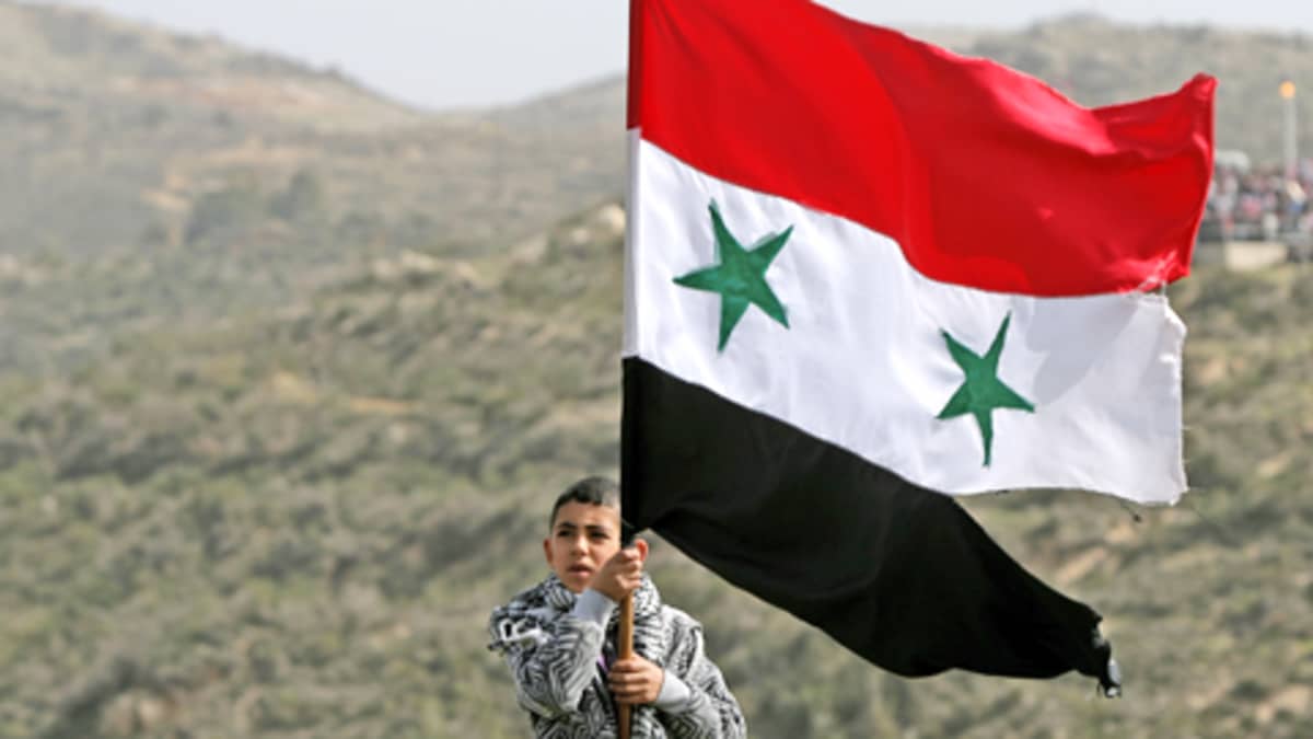 Nuori poika heiluttaa Syyrian lippua Golanin kukkuloilla.