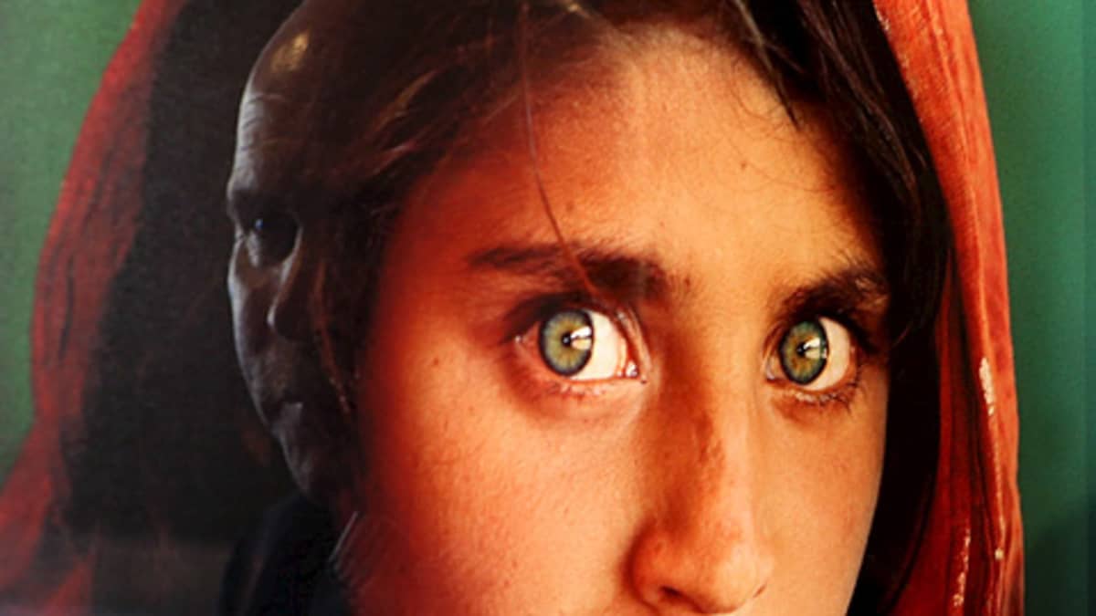 Afgaanityttö valokuvassa, joka lasin pinnasta heijastuu toiset kasvot
