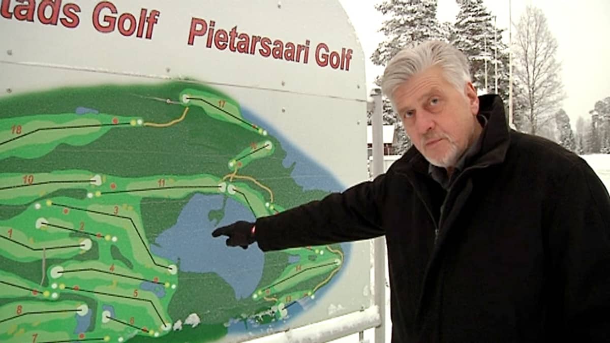 Kuvassa mies viisaa golf-kentän opastetaulua.