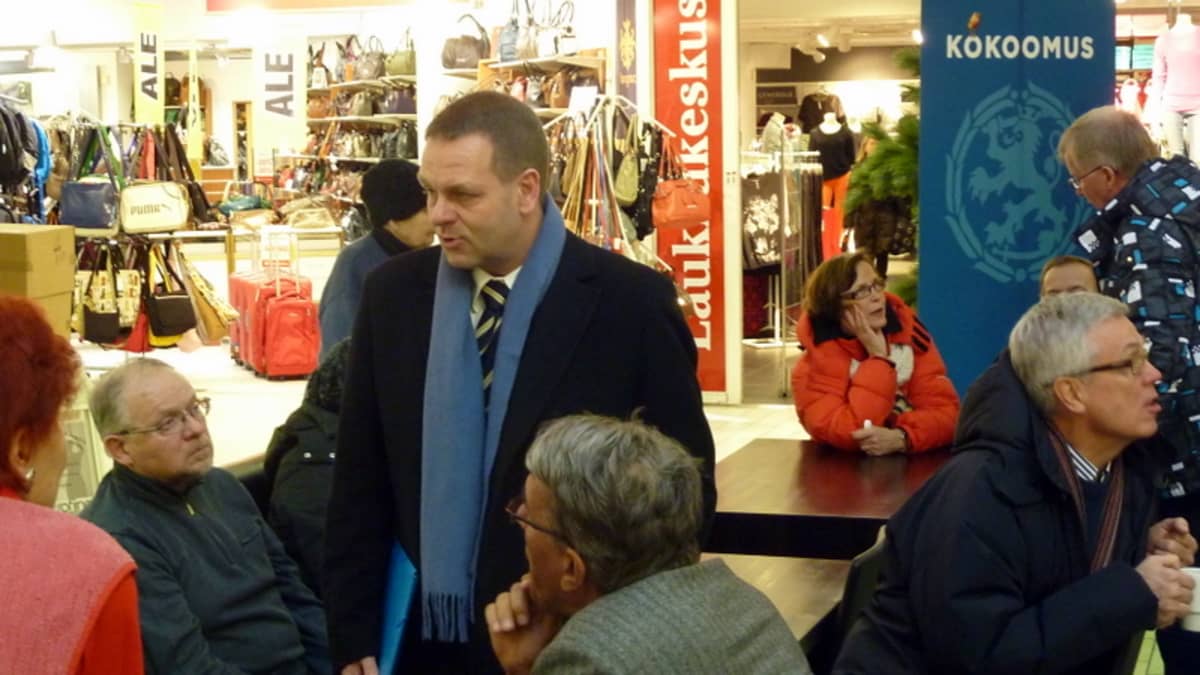 Elinkeinoministeri Jan Vapaavuori seisoo kahvilassa ja hänen ympärillään istuu ihmisiä.