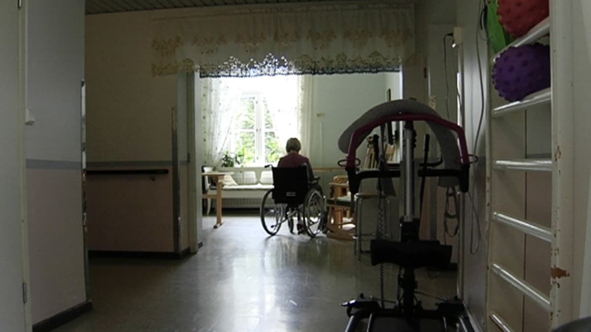 Yksinäinen vanhus istuu pyörätuolissa.