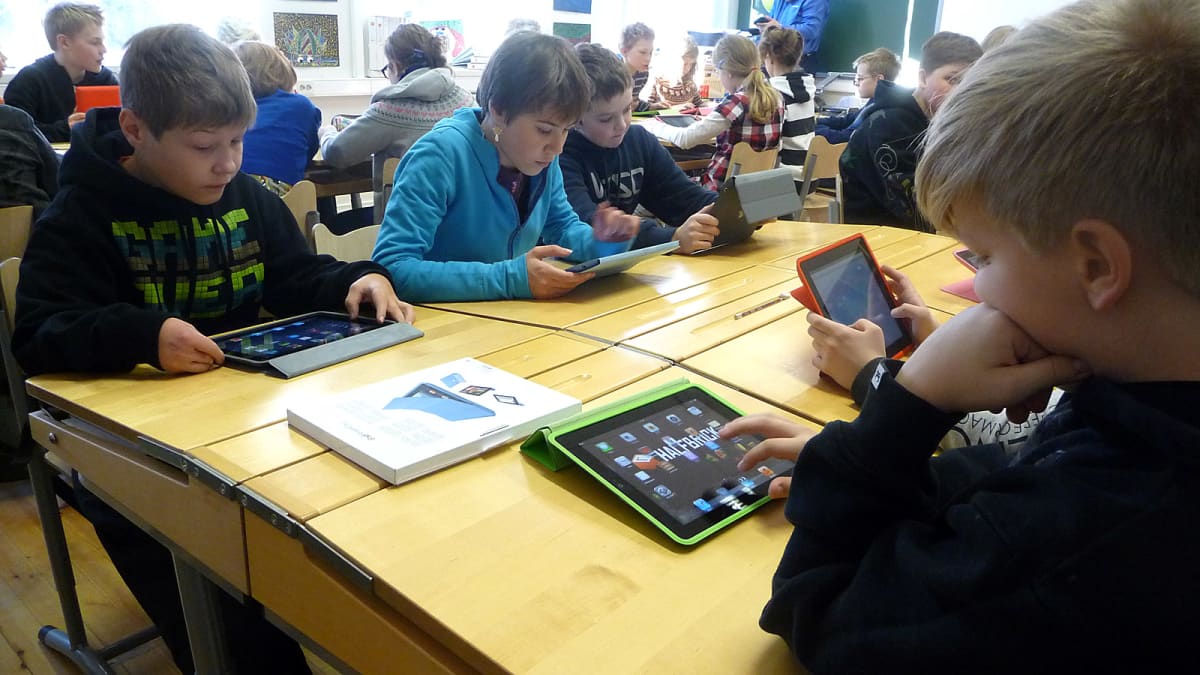 Lapsia pulpettien ääressä iPadien kanssa