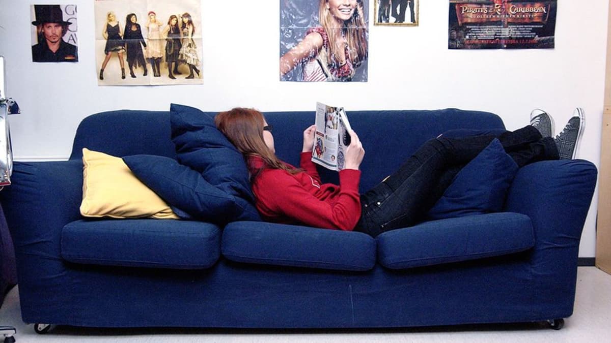 Nuori nainen lukee lehteä sohvalla.