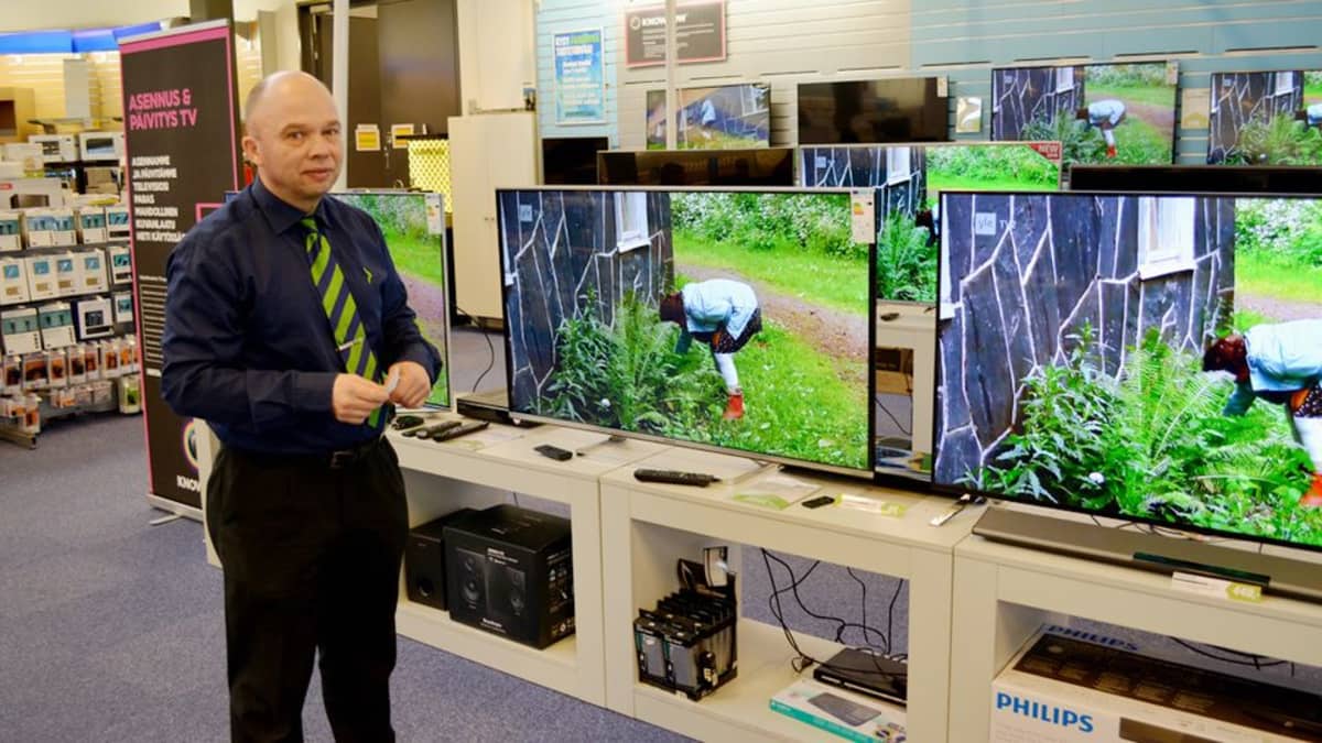 Teuvo Karhu esittelee televisioita elektroniikkamyymälässä.