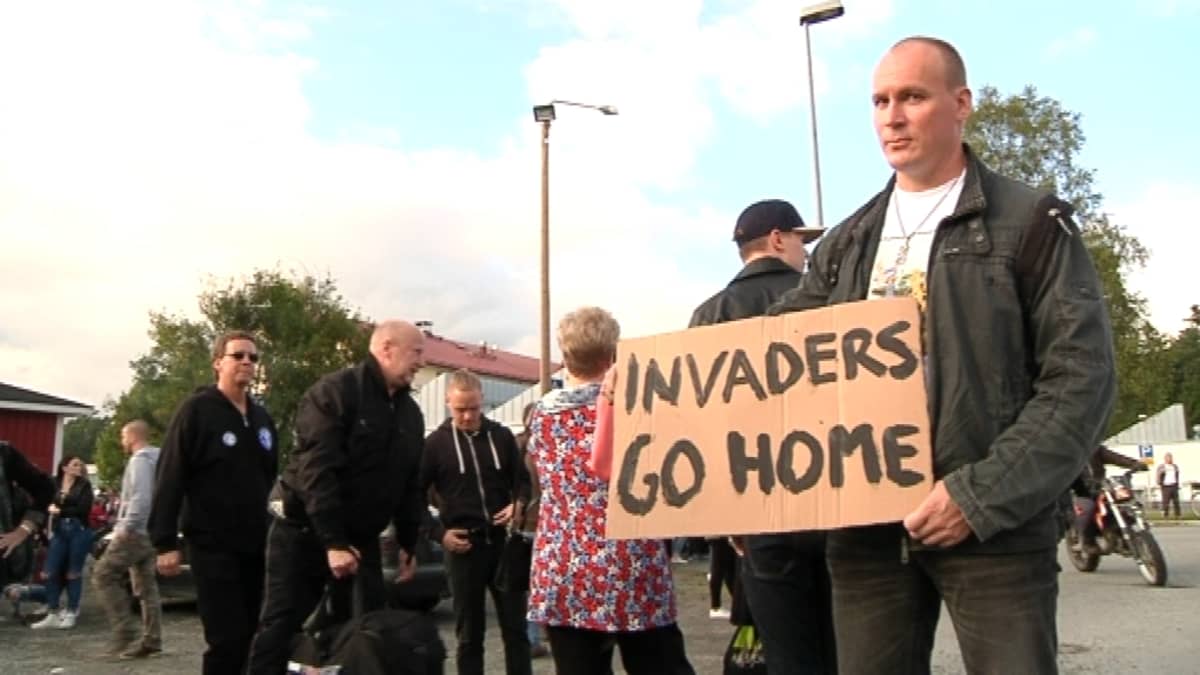 Mielenosoitus Forssassa, miehellä kyltti "Invaders go home"