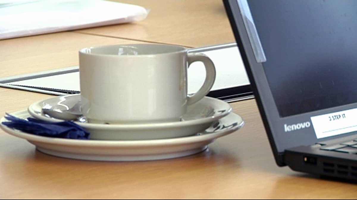 Kahvikuppi ja tietokone pöydällä.