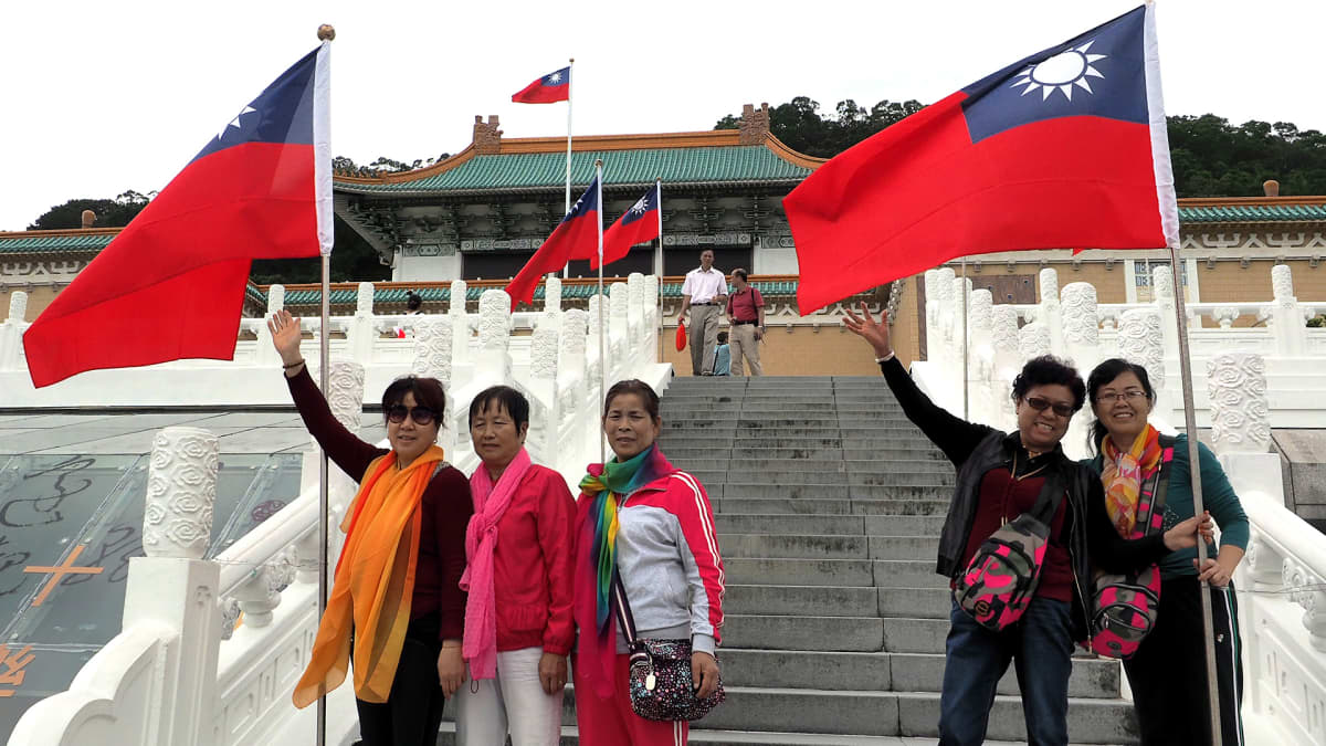 Kiinalaisturistit poseeraavat museon edessä.