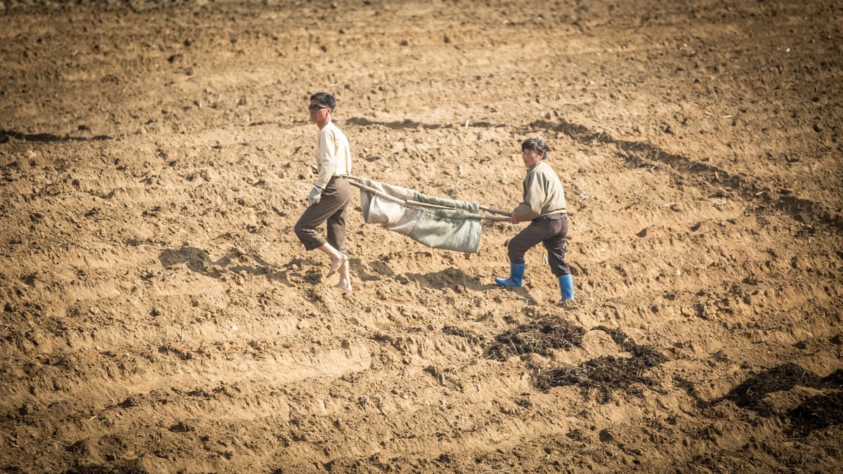 Kaksi miestä kuivalla pellolla.