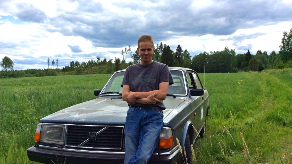 Pekka Holmström seisomassa auton edessä. Taustalla pelto. 