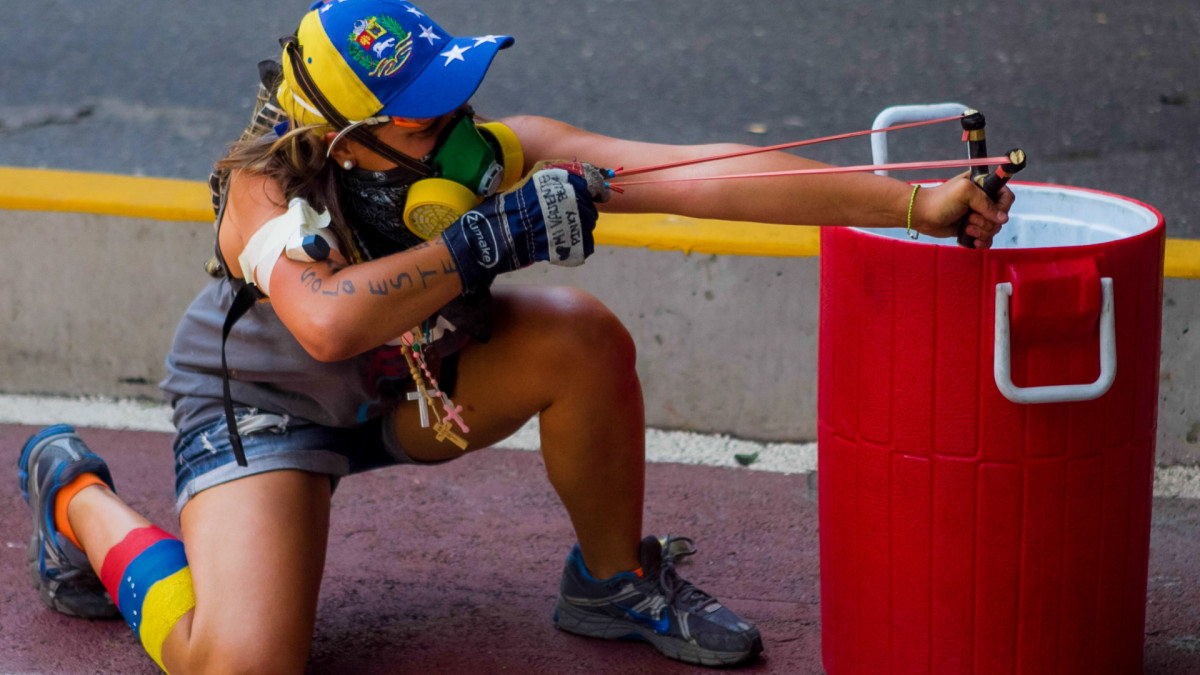Mielenosoittaja tähtää ritsalla poliiseja Caracasissa, Venezuelassa 12.4.2014