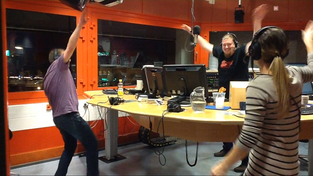 Kuvassa kolme ihmistä tanssii radiostudiossa.