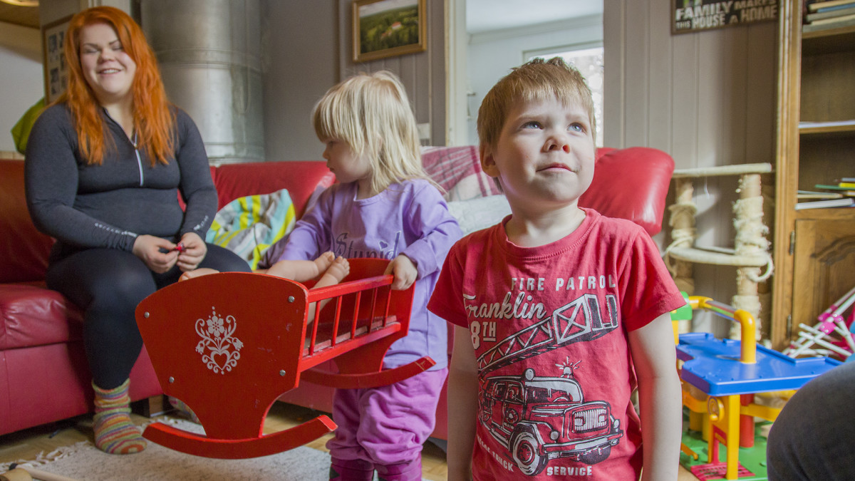 Lapset leikkivät ja äiti istuu sohvalla