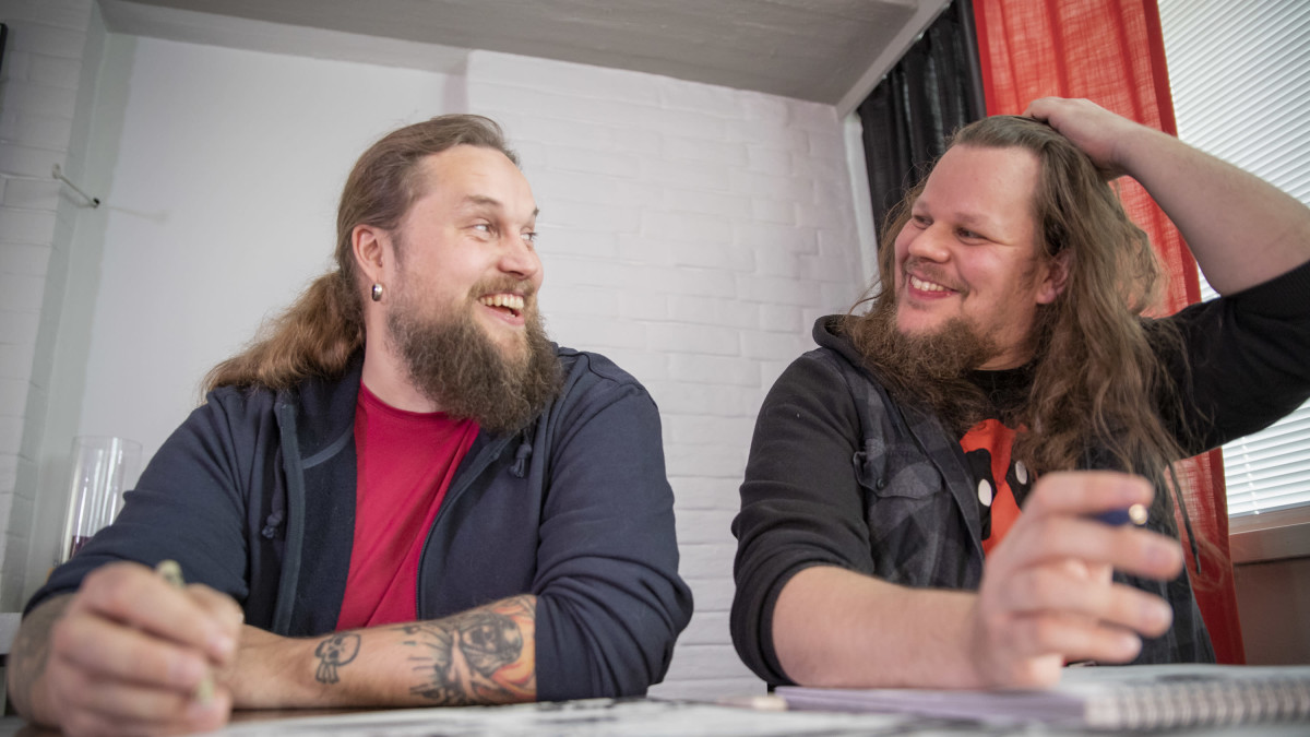 Roope-Santeri Nieminen ja Esa Turunen pöydän ääressä piirtämässä sarjakuvia iloisina.