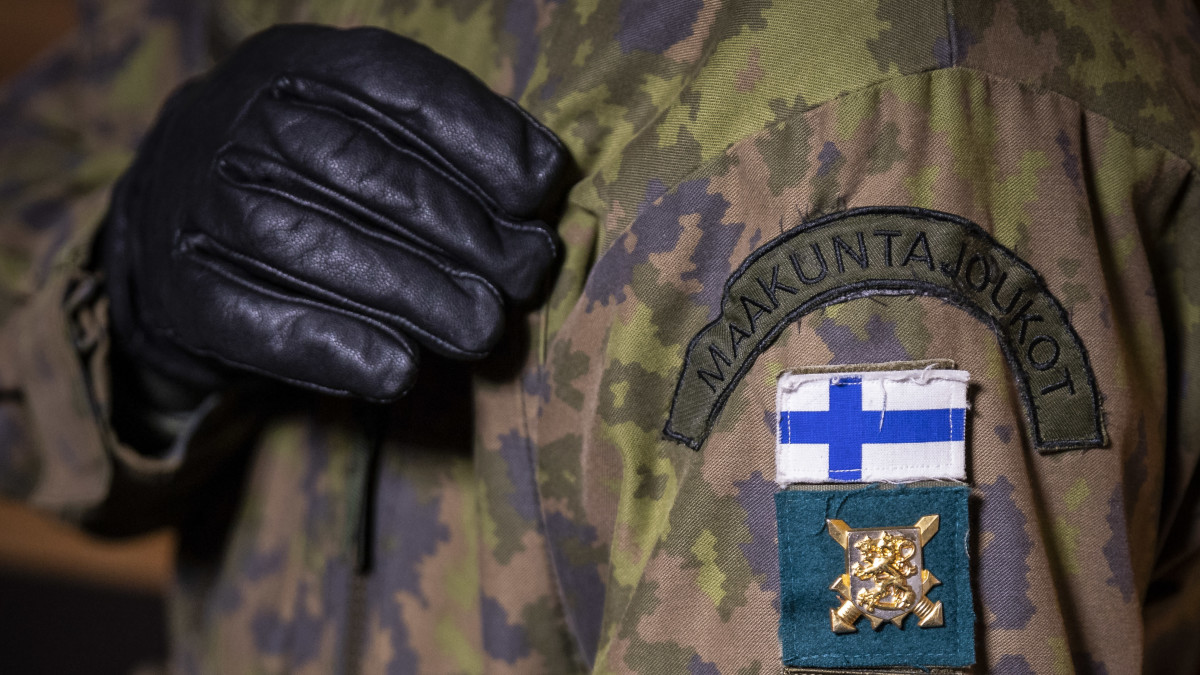 Hihassa siniristilippu ja maakuntakomppanian soikea merkki, missä kärppä ja viisi ristiä.
