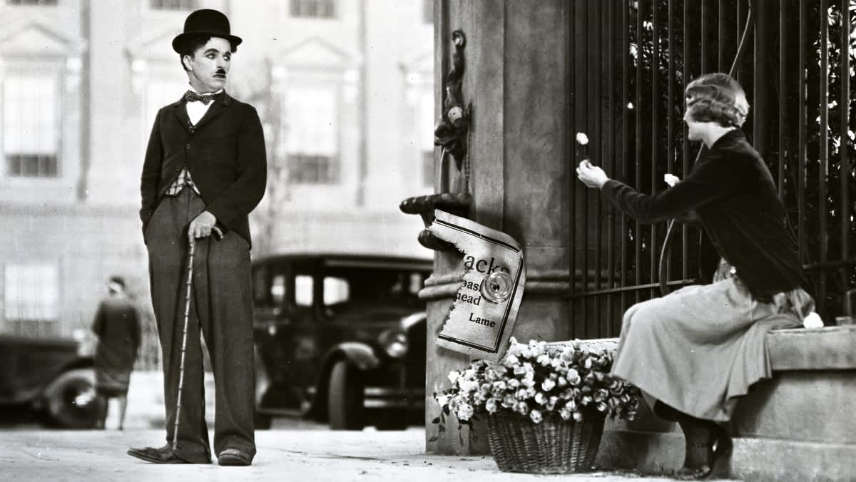 Charlie Chaplin katsoo sokeaa tyttöä joka ojentaa hänelle kukkasen.