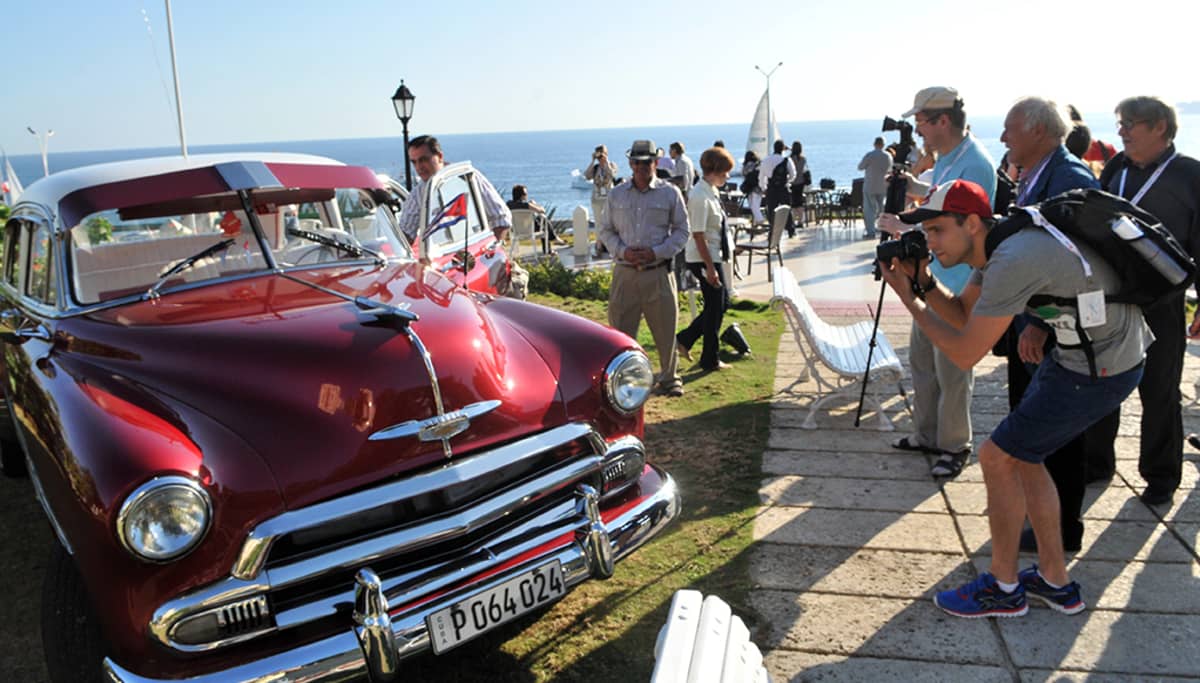 Turistit kuvasivat vanhaa autoa Havannassa toukokuussa 2014.
