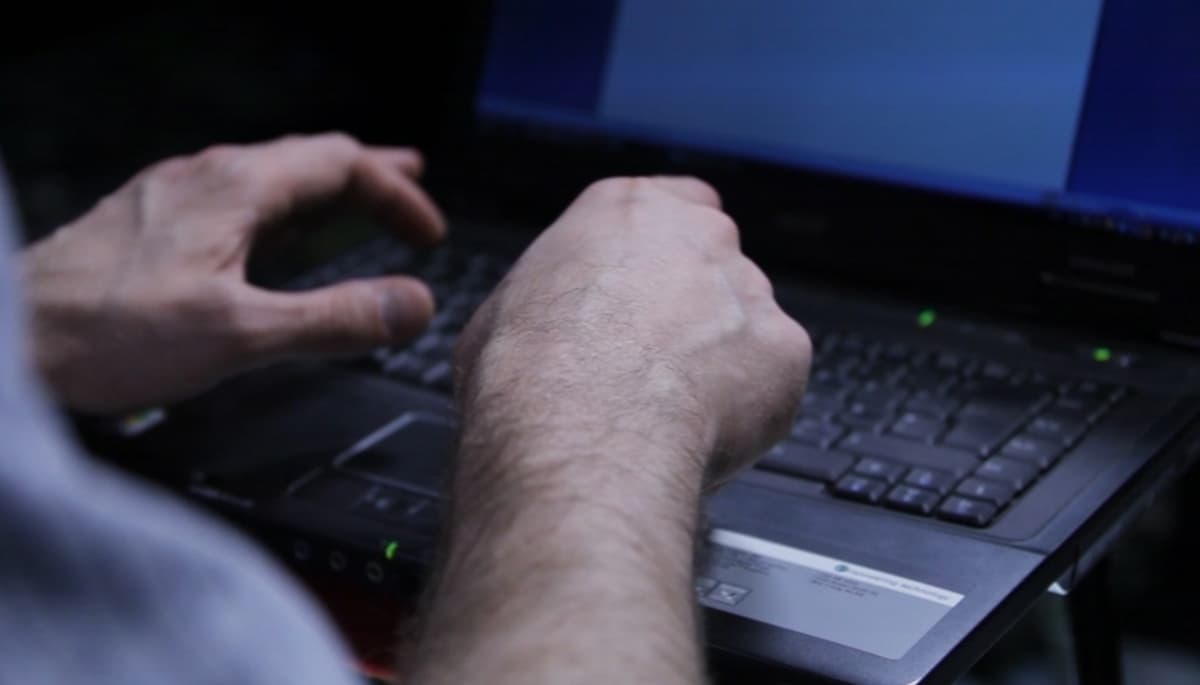 Mies kirjoittaa tietokoneella.