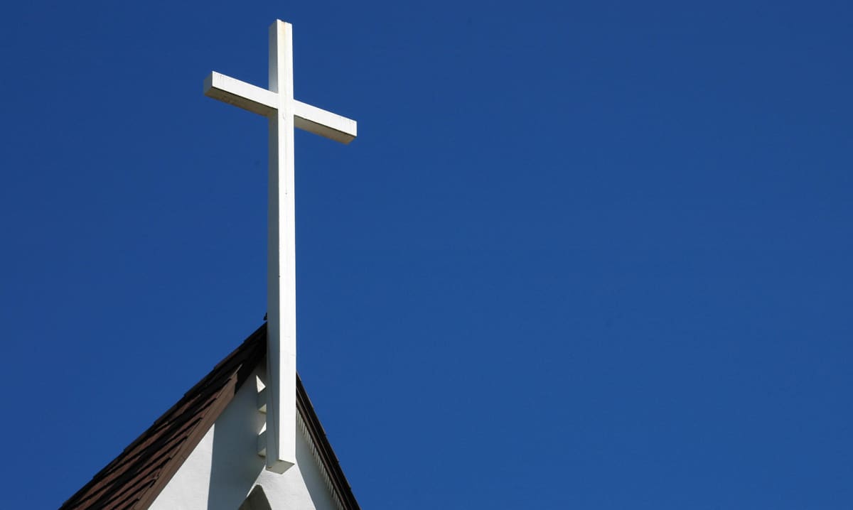 Valkoinen risti kirkon katolla sinitaivasta vasten