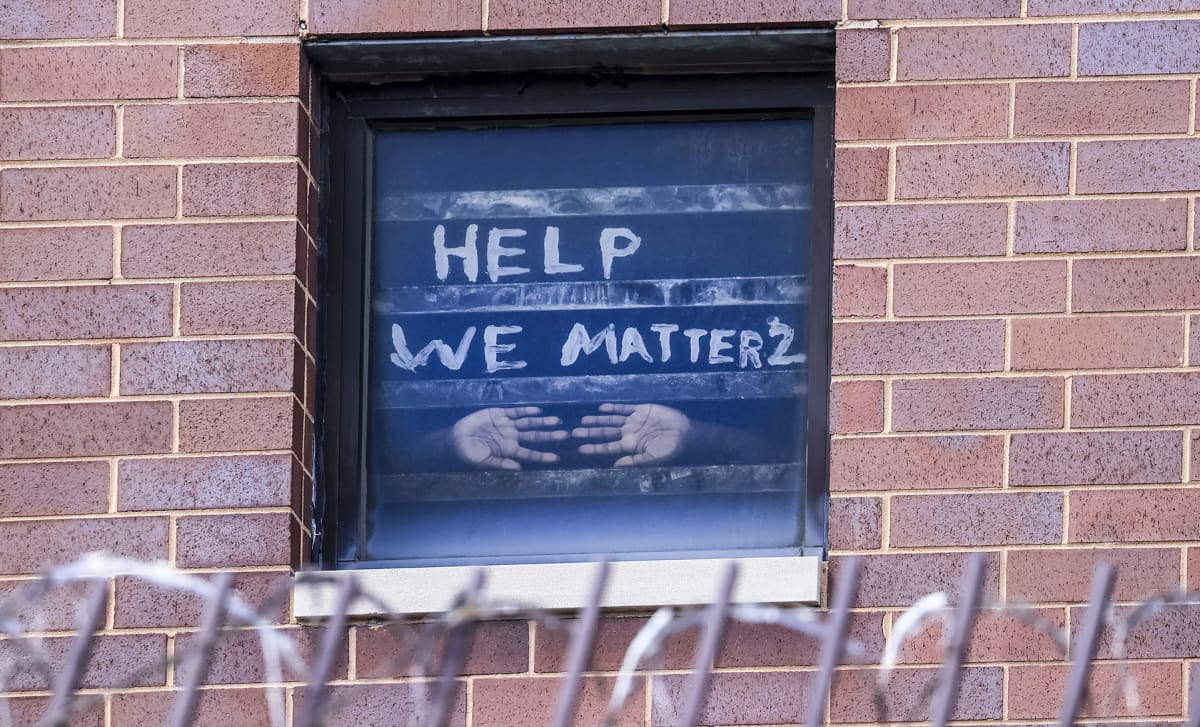 Vangin kädet vankilan ikkunassa tekstin alla jossa lukee "help, we matter".