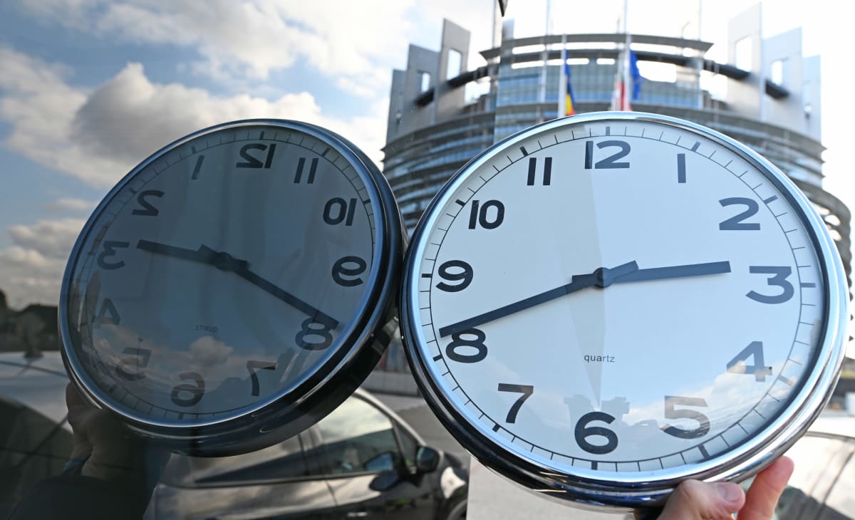 Kello heijastuu lasiseinästä ja taustalla näkyy EU rakennus Strasbourgissa.