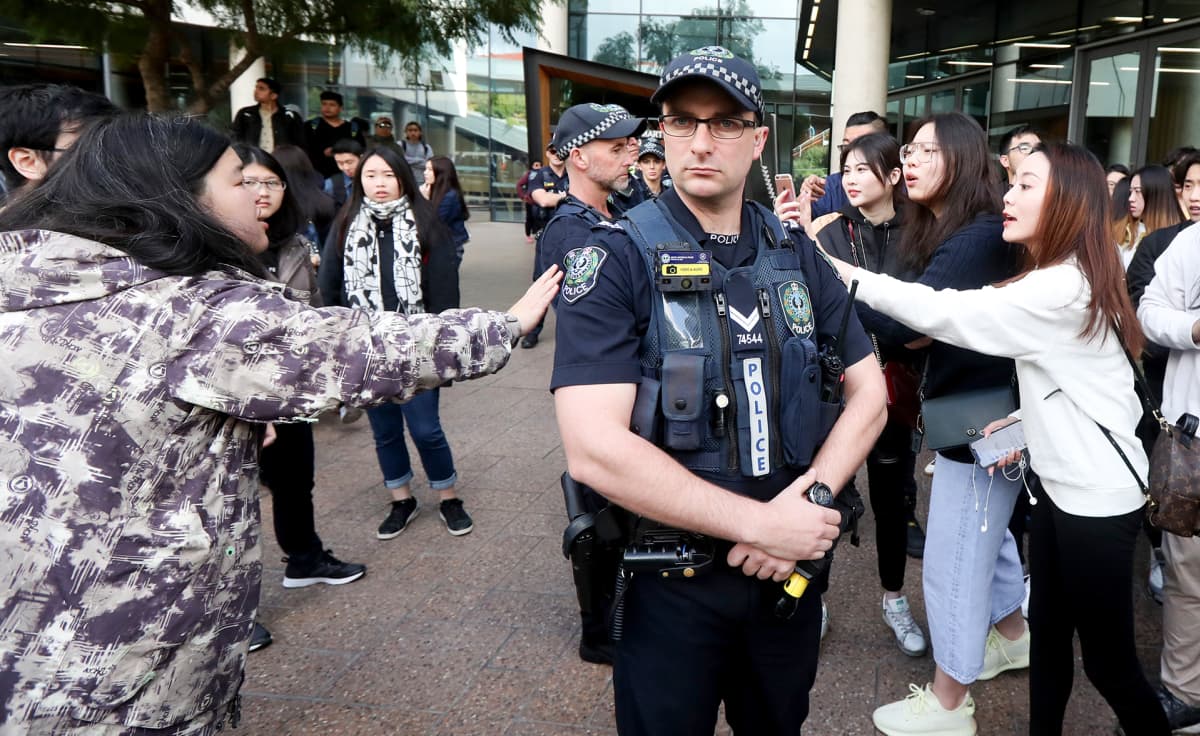 Australian poliisi seisoo protestoijien välissä.