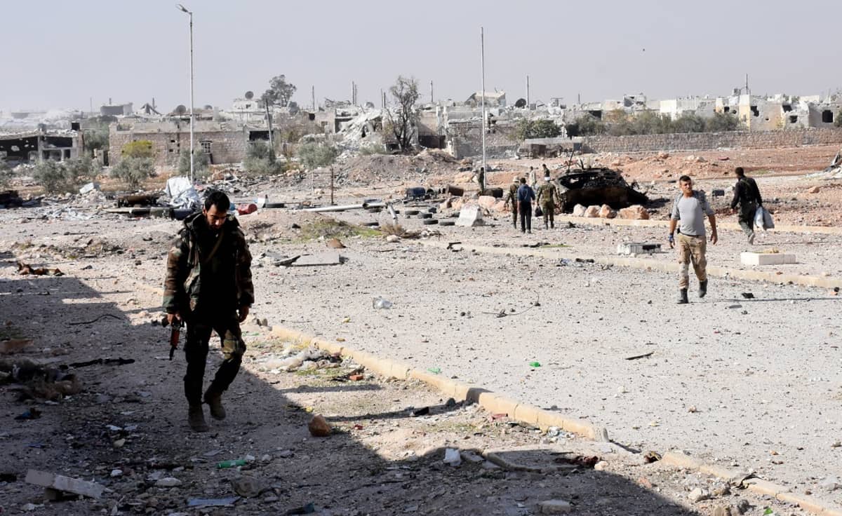 Sotilaita kävelee Aleppon kaupungin raunioilla. Taustalla raunioita ja palanut auto.