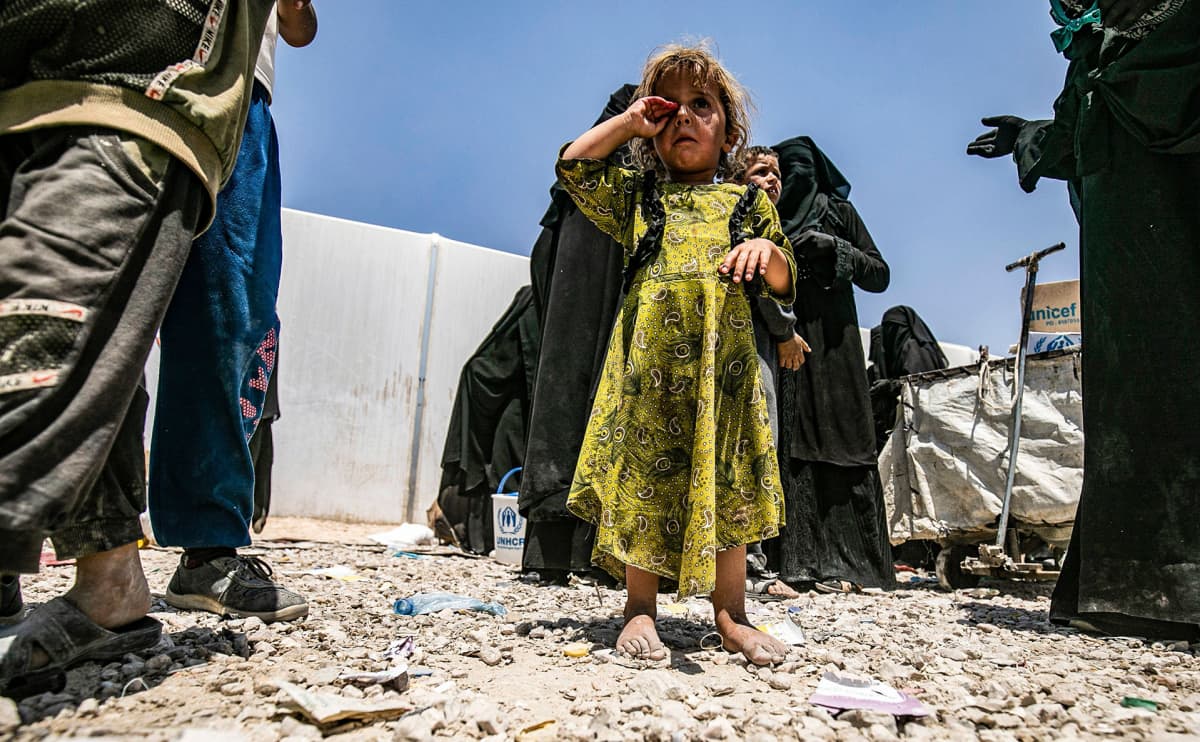 Syyrialainen pikkutyttö seisoo avojaloin kameran edessä hieroen itkuisia silmiään al-Holin pakolaisleirillä Syyriassa.