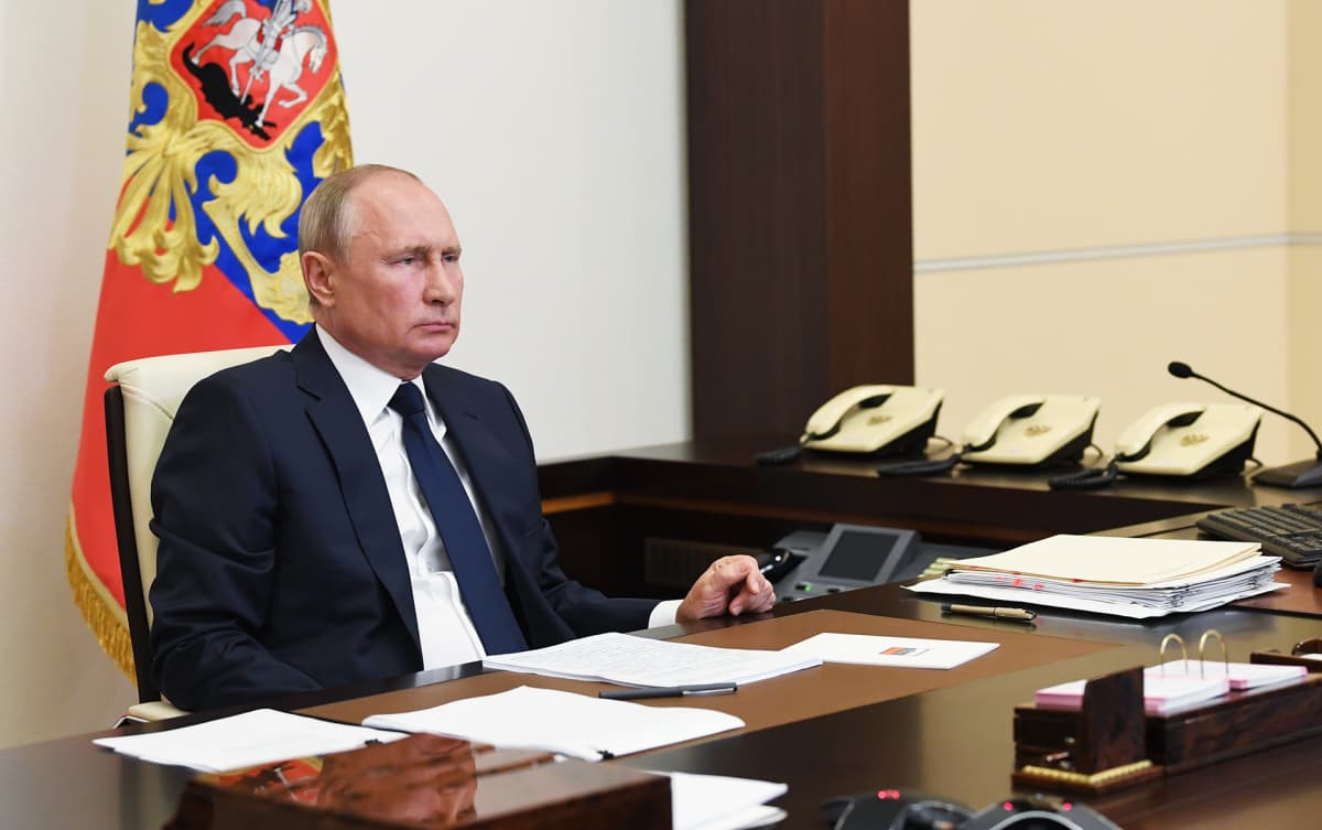Vladimir Putin istuu työpöytänsä ääressä.