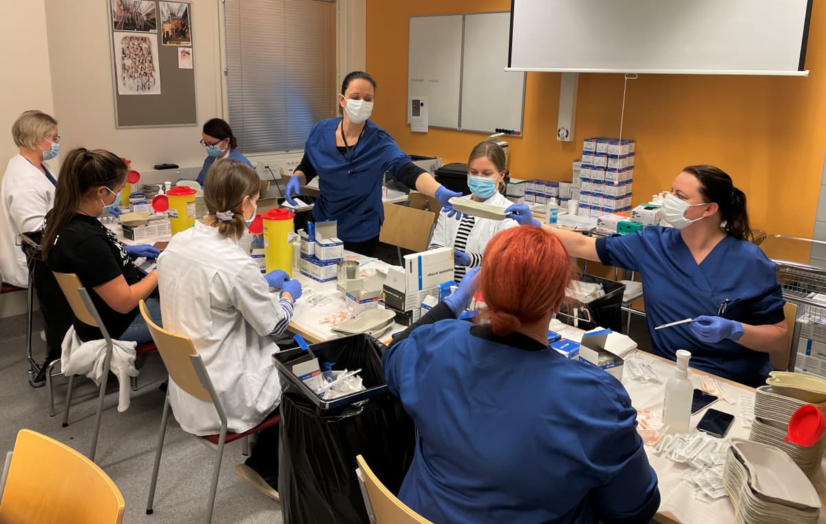 Seinäjoen terveyskeskuksen työntekijät annostelevat koronarokotteita valmiiksi annoksiksi rokotustapahtumassa.