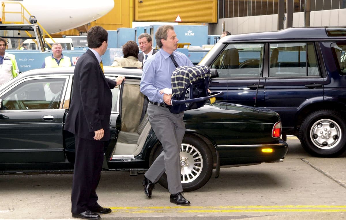 Tony Blair kantaa vauvan turvakaukaloa Heathrown lentoasemalla.