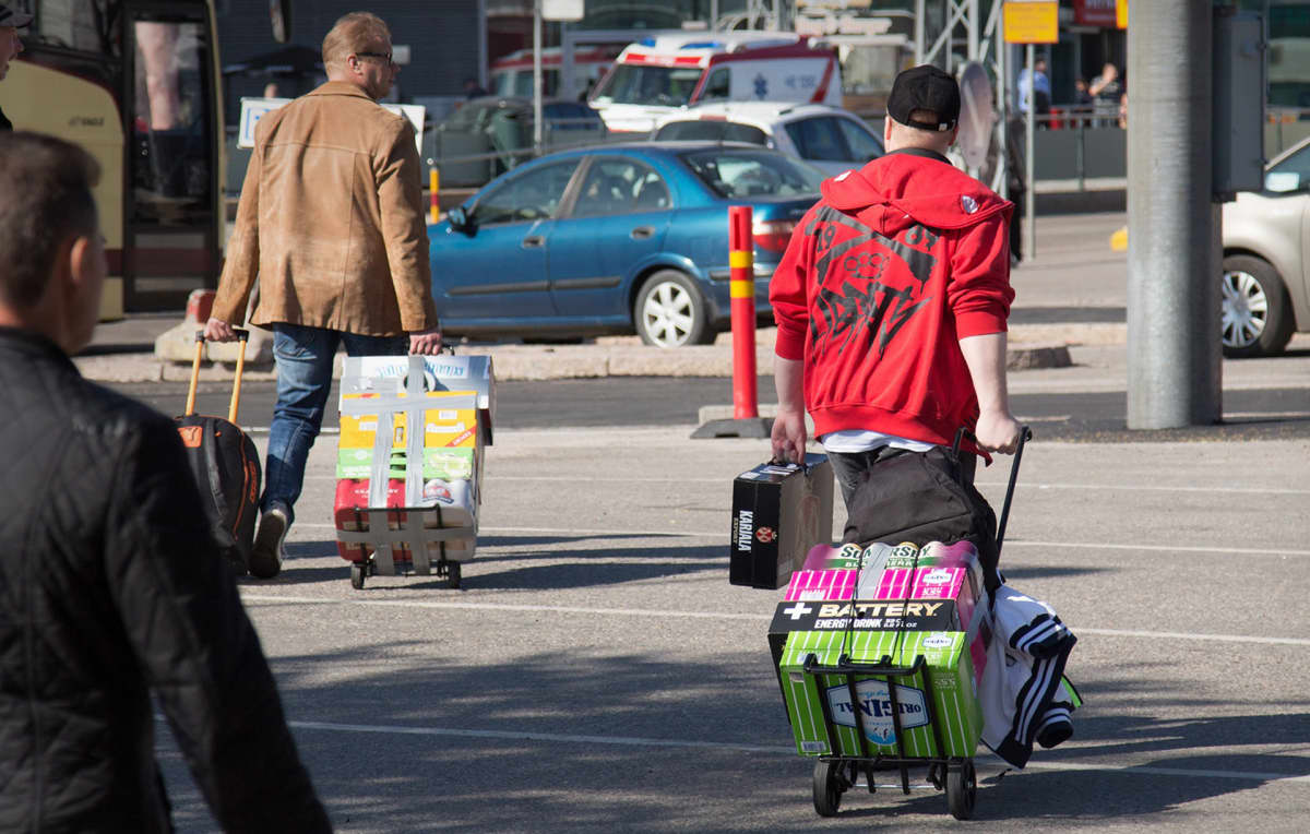 matkustajat kantavat olutlastia satamassa